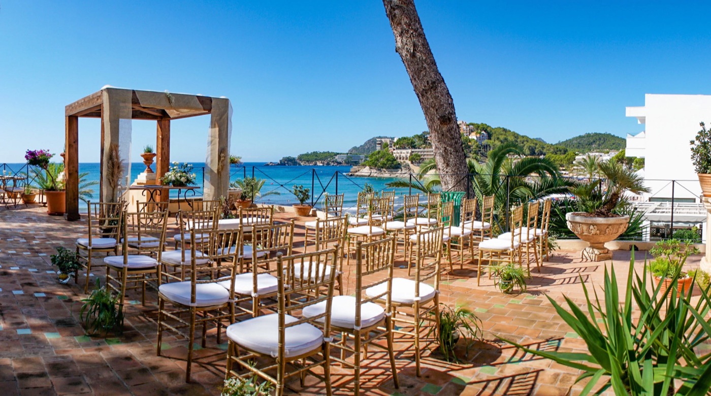 Ocean-view destination wedding ceremony with a wooden gazebo and gold chairs